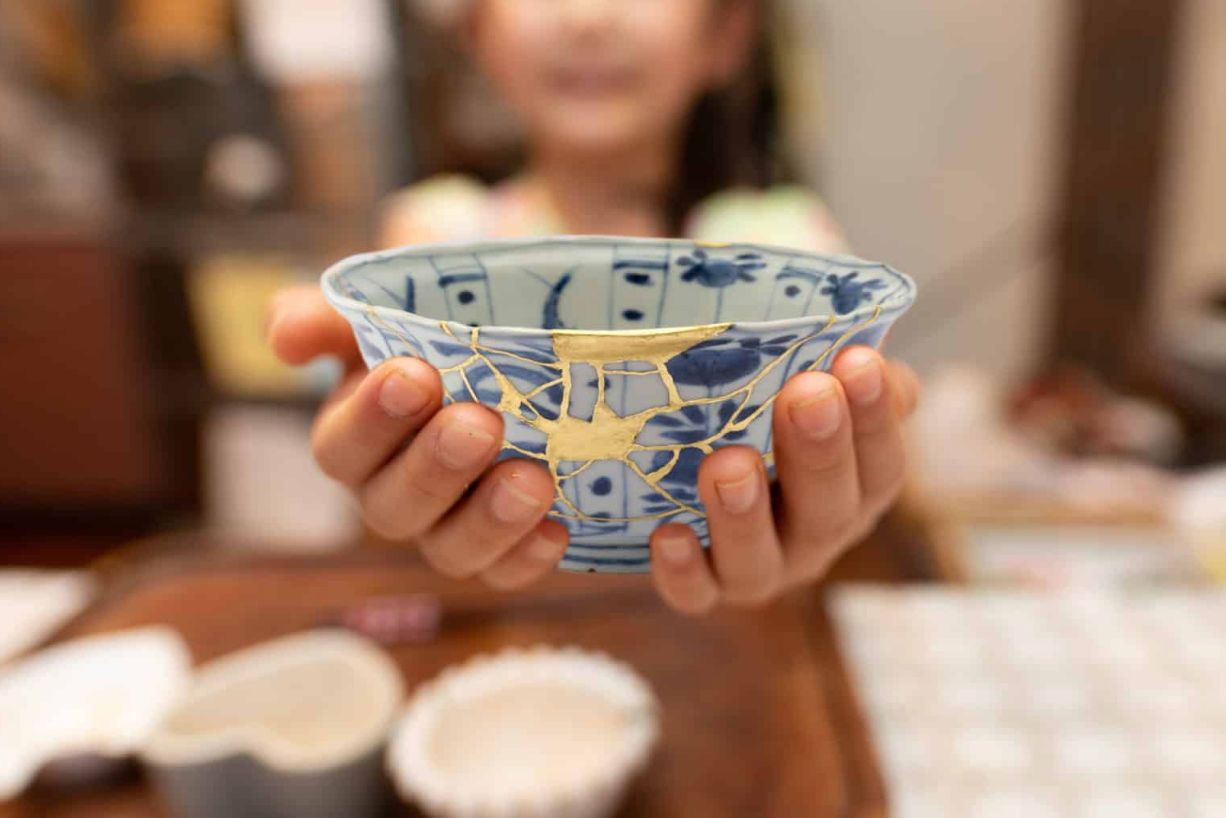 girl holding a broken and repaired bowl, representing beauty in the brokenness